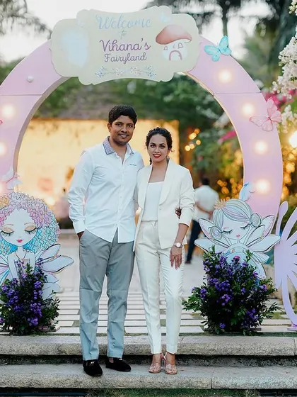The happy parents posing at the entrance of their daughter's fairyland party. The custom arch with butterfly-winged fairies creates a stunning photo opportunity and sets the stage for the celebration.