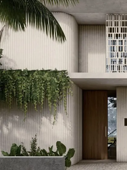 A detail of the entrance to one of the Pavilion homes. The facade juxtaposes the texture of fluted concrete walls, the pattern of perforated screens, and the softness of hanging greenery, creating a rich material composition.