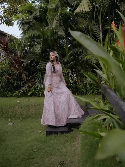 A full-length portrait of a bride in a beautiful pink gown, posing in a garden.