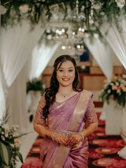 A smiling bride in a beautiful lavender saree, ready for her reception.