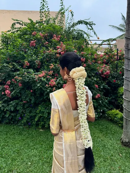 A classic South Indian bridal hairstyle featuring a long, thick braid adorned with a full garland of fresh jasmine flowers (Malli Poo). This is a timeless and fragrant choice for a Muhurtham.