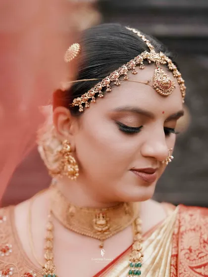 A close-up of a South Indian bride, her face adorned with traditional jewelry.
