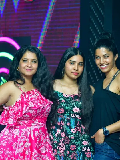 A stylish group of ladies posing for a photo against the neon backdrop of the club. The venue's aesthetic complements the vibrant music.