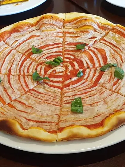 A visually striking pizza with a spiral of tomato sauce and my homemade vegan cheese, garnished with fresh basil.