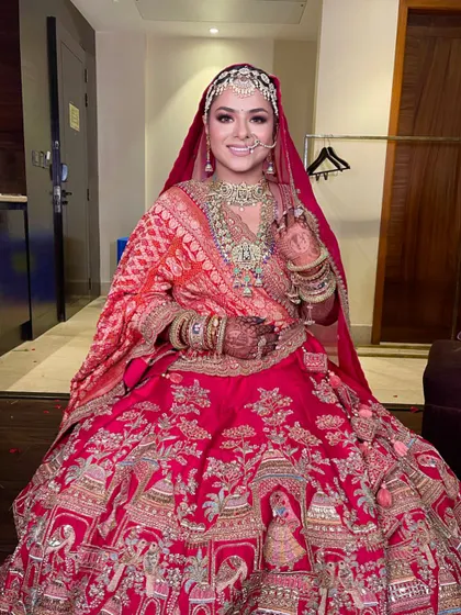 A happy bride on her wedding day, looking absolutely radiant in her traditional red outfit and classic hairstyle.