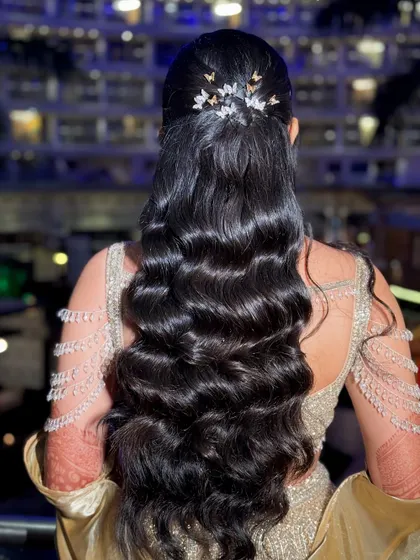 A glamorous half-up hairstyle with long, flowing waves, decorated with butterfly clips for a touch of whimsy.