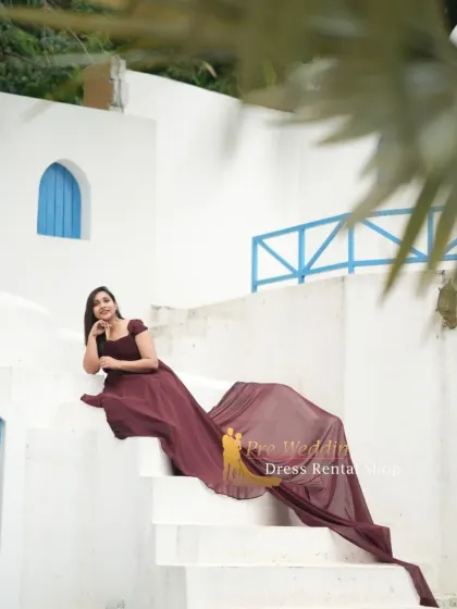 A seated pose on white steps, with the maroon trail gown cascading down. This shows how the long tail can be used to create elegant, draped compositions even in static poses.