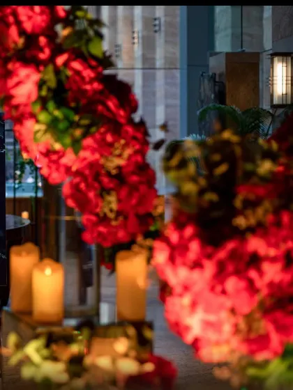 A close-up of the welcome signage and rich red floral arrangements for a Sangeet ceremony. Clear signage and beautiful entrances ensure guests feel welcomed from the moment they arrive.