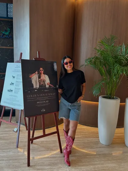 A happy pose next to my event poster in Oman, marking the end of a successful international residency.