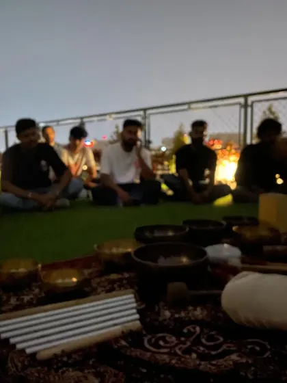 Participants at the rooftop session, listening intently as I explain the different instruments. The city lights of Bangalore twinkle in the background, creating a magical atmosphere.