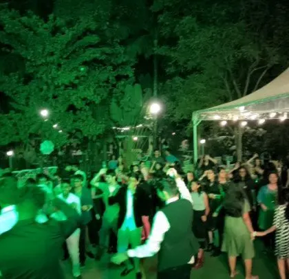 A farewell party with guests dancing under outdoor tents.