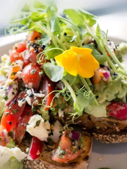 A vibrant avocado toast, loaded with fresh salsa, feta cheese, and microgreens. A popular and healthy option for brunch events.