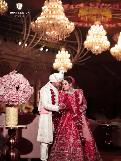 A grand, romantic portrait of the couple under magnificent chandeliers, lost in their own world on their wedding day.