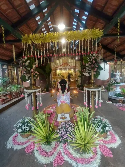 The central setup for the ceremony, featuring a beautiful floral rangoli made of fresh petals, traditional lamps, and arrangements of auspicious plants and flowers.