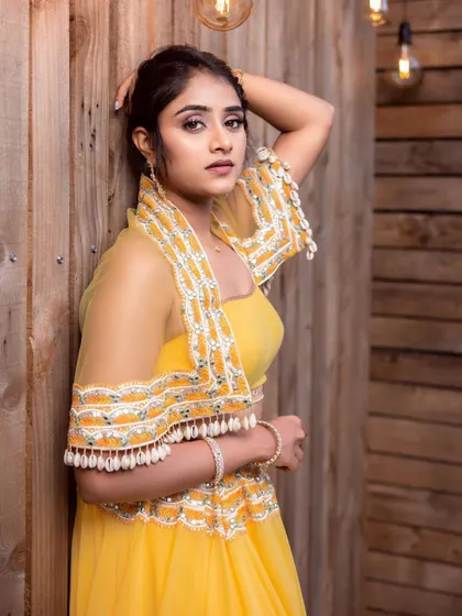 A model in a bright and sunny yellow lehenga with a stylishly embroidered cape-style dupatta.