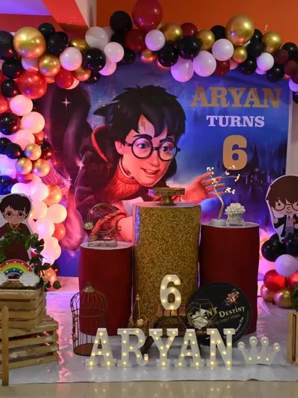 The full view of our Harry Potter setup, complete with a balloon garland in Gryffindor colors, themed pedestals, and light-up letters for the birthday boy's name.