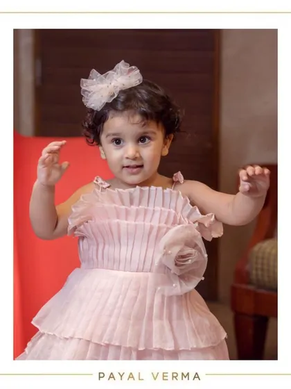 This little muse looks absolutely dreamy in her blush pink organza dress for her second birthday. The dress features delicate pleating on the bodice and a tiered skirt for extra twirl factor.