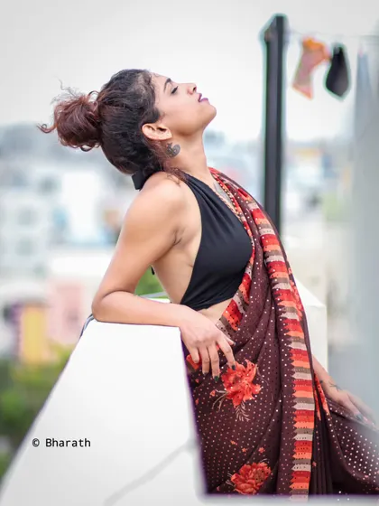 A relaxed and sensual rooftop saree portrait, capturing a moment of calm with an urban backdrop.