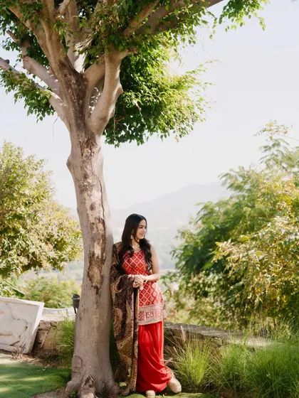 A smiling, relaxed pose in the red kurta set, showing a comfortable and graceful look.