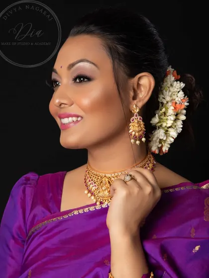 The art of beauty is timeless. This studio portrait showcases a classic South Indian look with a purple saree, temple jewellery, and a floral bun, all brought together with soft, elegant makeup.