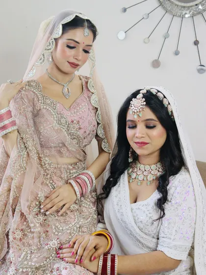 Two beautiful brides, one in a soft pink and the other in a classic white. This shows my versatility in creating distinct looks that suit each bride's individual style and outfit.
