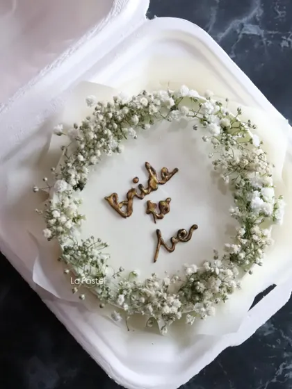 A delicate 'Bride to Be' bento cake, decorated with a wreath of fresh baby's breath. It's a sweet little cake for a bridal shower or pre-wedding celebration.