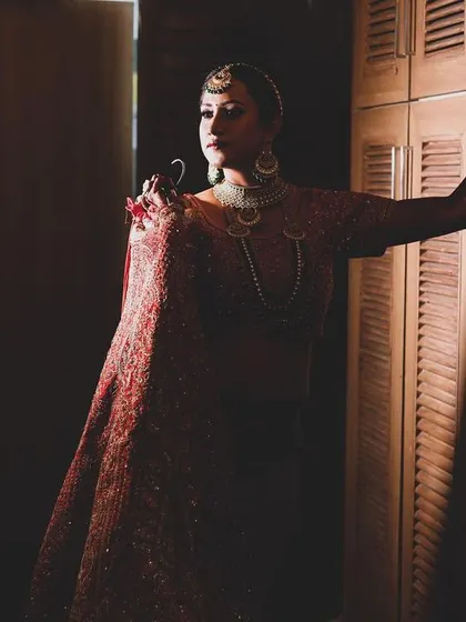A powerful bridal portrait using dramatic side lighting to create deep shadows. The bride's confident pose and the moody atmosphere make for a striking image.
