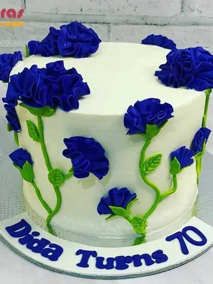 A beautiful floral cake with vibrant blue buttercream flowers climbing up the side. This design is a lovely way to celebrate a 70th birthday with natural elegance.