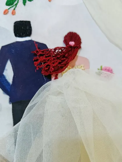 A detailed view of the Western wedding hoop, focusing on the bride's red hair made of thread and the flowing tulle veil.