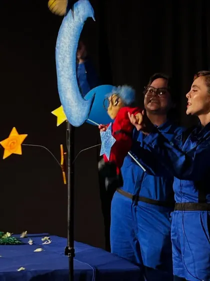 A close-up of the puppeteers from 'Volar Volar' interacting with the main puppet, Greta, and other celestial characters.