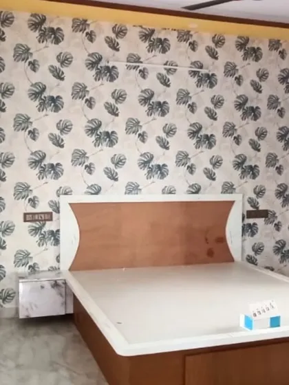 This bedroom features a stylish monstera leaf pattern wallpaper. The dark green leaves on a light background create a fresh, contemporary look that's very popular for modern home decor.