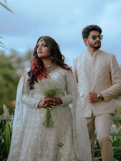 A stylish couple poses against a backdrop of lush greenery, showcasing a modern and chic wedding look.
