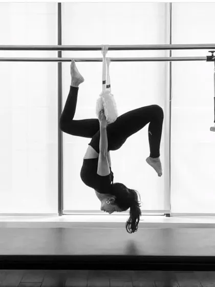 A black and white shot of a hanging inversion on the Cadillac. This move is not only a great workout but also feels incredibly restorative for the spine.