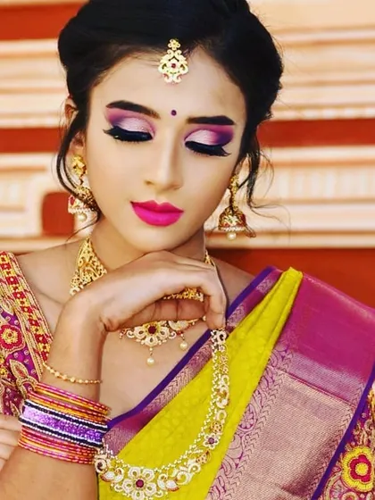 A close-up on the details of a dramatic bridal look. The vibrant pink and purple eyeshadow is blended to create a bold statement, perfectly matching the bride's colorful saree and enhancing the overall festive feel.