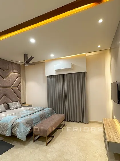 A full view of the bedroom, showcasing the balance between the statement headboard, the simple TV unit, and the soft grey curtains.