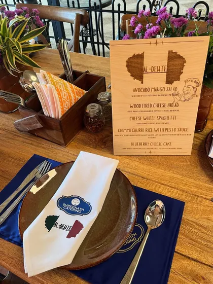 A personalized table setting for our 'Al-Dente' fine dining concept, complete with a custom wooden menu featuring dishes like Avocado Mango Salad and Wood Fired Cheese Bread.