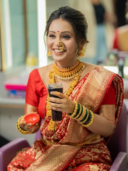 A candid moment of the bride taking a quick break, her genuine smile captured as she enjoys a refreshing drink.