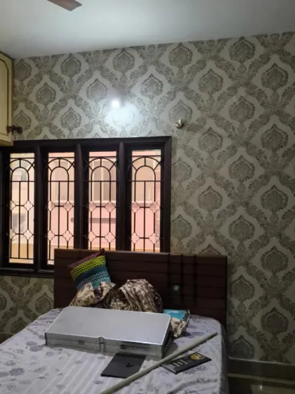 A full view of the bedroom, showing the grey damask wallpaper.
