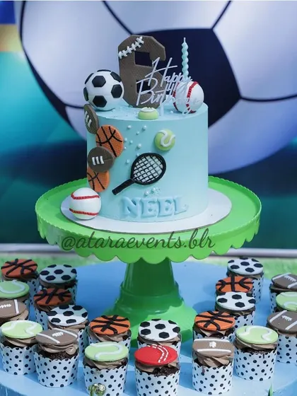 A sports-themed cake and cupcakes for a 6th birthday. The cake is decorated with various sports balls and a tennis racket, and the cupcakes have matching toppers, perfect for a little sports enthusiast.