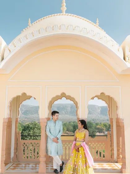 A pre-wedding portrait using the stunning architecture of a palace balcony to frame the couple against a backdrop of distant hills.