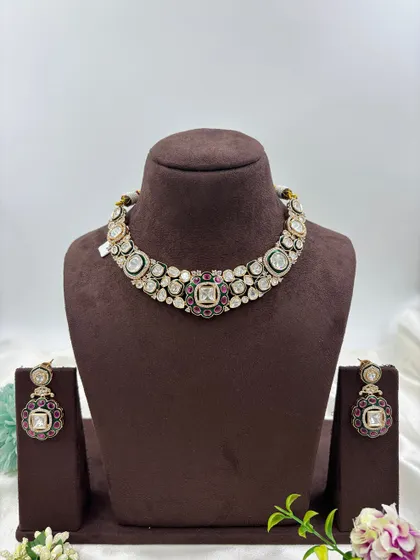 A close-up look at the fine detailing on this Moissanite and Kundan choker. The combination of large uncut stones with a ruby and emerald green center makes it a classic and highly sought-after design.