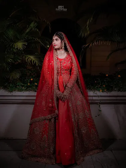 A full-length portrait of the bride in her magnificent red lehenga, showcasing its grandeur.