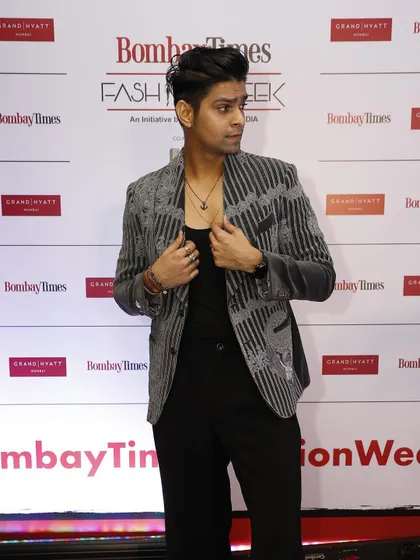 This red carpet shot shows how the grey velvet coat catches the light, emphasizing the rich texture of the fabric and the intricacy of the hand-stitched details.