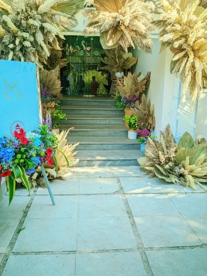 A modern and rustic entrance decoration for a party. I used dried pampas grass and other florals to frame the steps leading to the venue, with a welcome board on an easel.