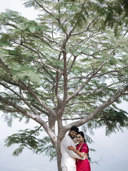 A wider shot of the couple under the tree, showing the full beauty of the natural setting for their engagement photos.