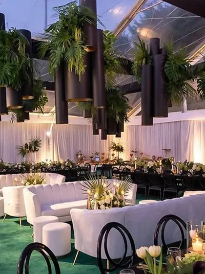 A chic lounge setup with white sofas, a green carpet, and dramatic overhead foliage. This shows how our venue can be transformed into a stylish, contemporary jungle-themed oasis for a unique party experience.