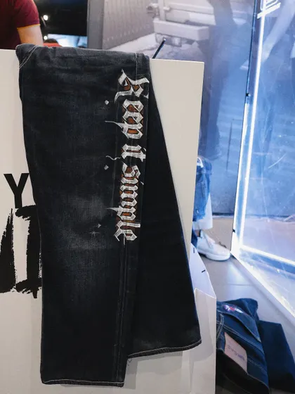 A close-up of customized graffiti art on a pair of dark wash jeans.