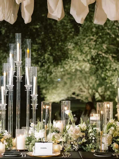A tablescape glowing with dozens of candles in tall glass holders, creating a forest of light that is both dramatic and romantic.