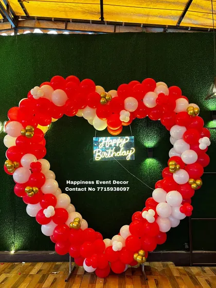 A large, heart-shaped balloon arch is a bold and romantic statement piece. I built this one with red and white balloons against a green wall, complete with a neon sign, perfect for anniversaries or proposals.