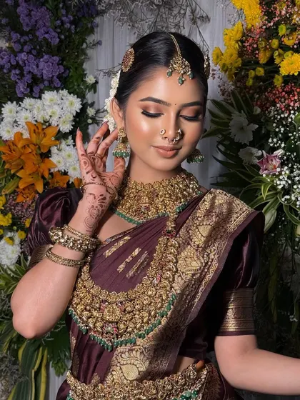 A close-up of the bride in her wine-colored Kanchivaram, showing the intricate details of the saree's border and the temple jewellery.